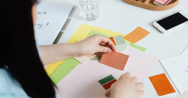 Une personne organise des papiers colorés sur une table blanche avec des fournitures artistiques